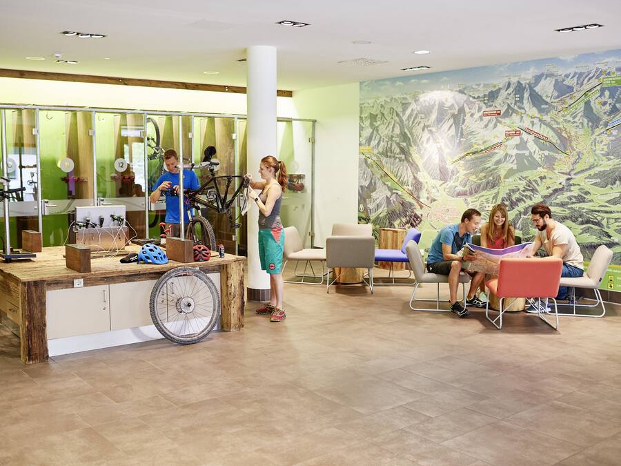 Una habitación con un escritorio de madera, bicicletas y un mural grande con un paisaje montañoso.