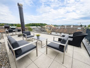 A rooftop terrace with outdoor furniture, a grill, and a view of the cityscape. - Gasthof zum Hecht (Fehraltorf)