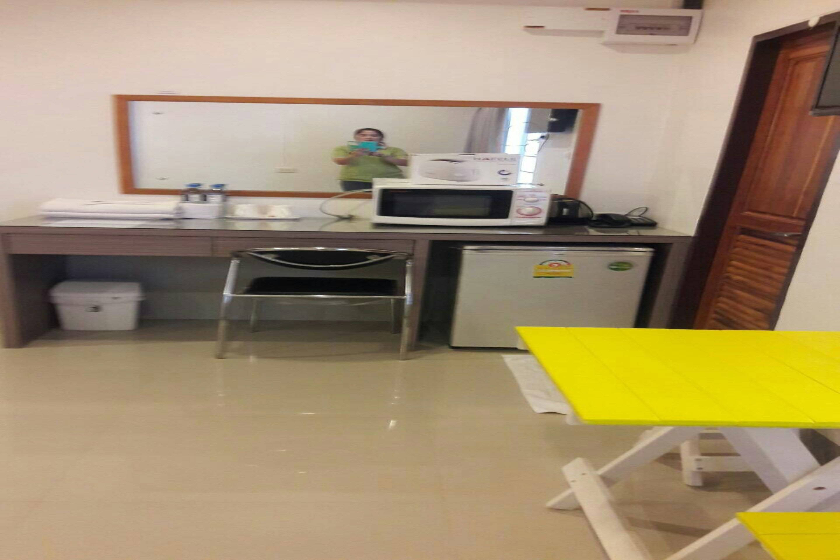 A small kitchenette with a microwave, refrigerator, and a chair.