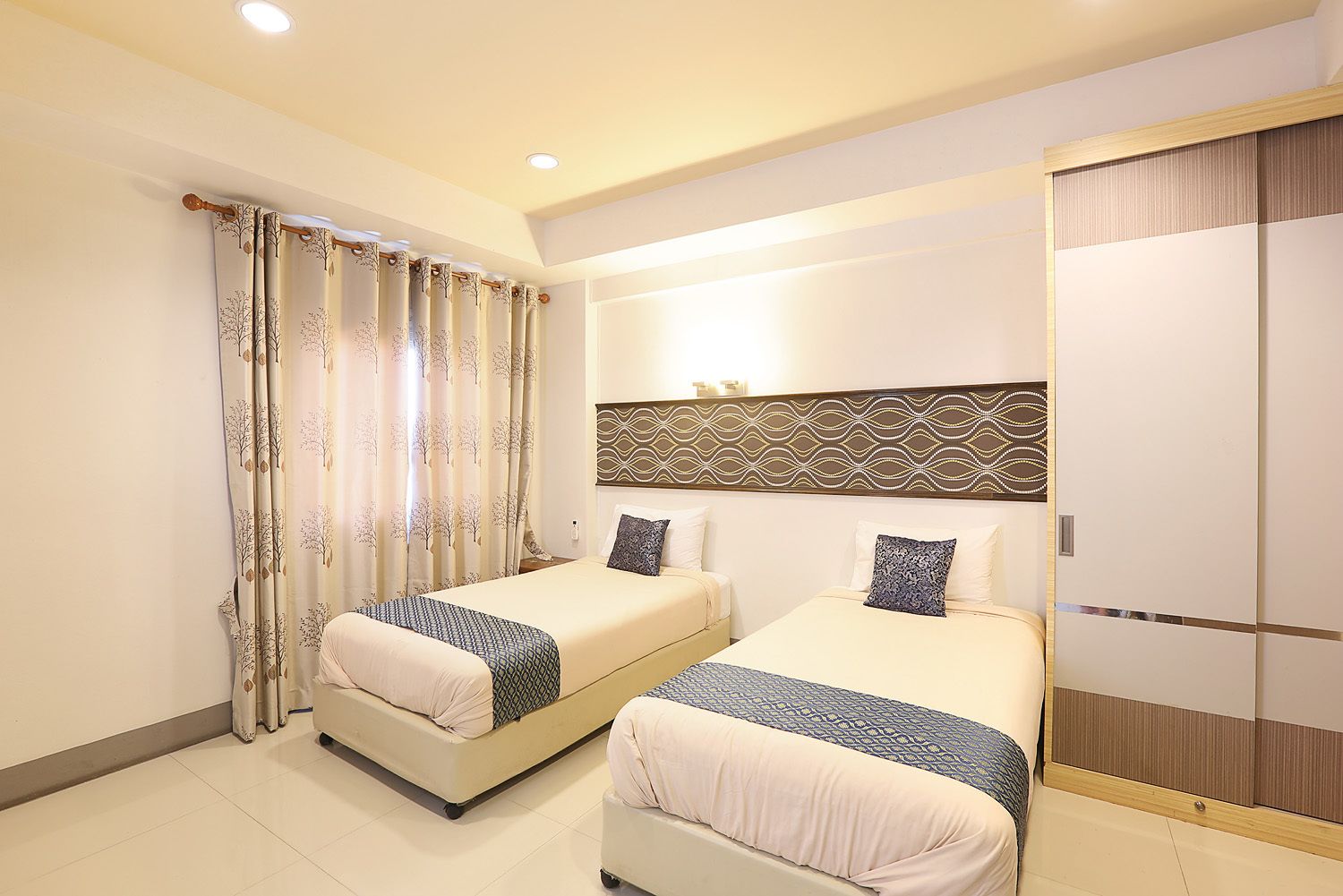 A hotel room with two beds, a large mirror, and a wardrobe.
