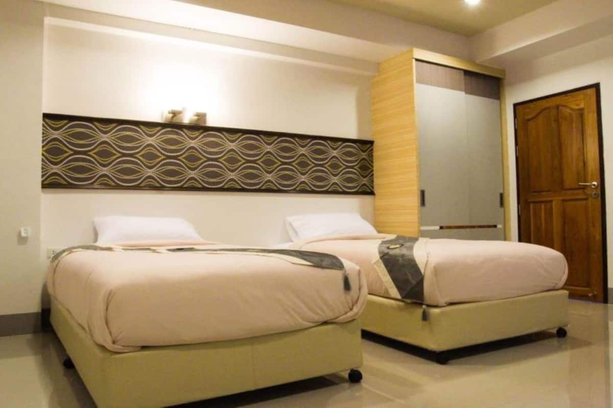 Une chambre d’hôtel avec deux lits, un panneau décoratif au mur et une porte en bois.