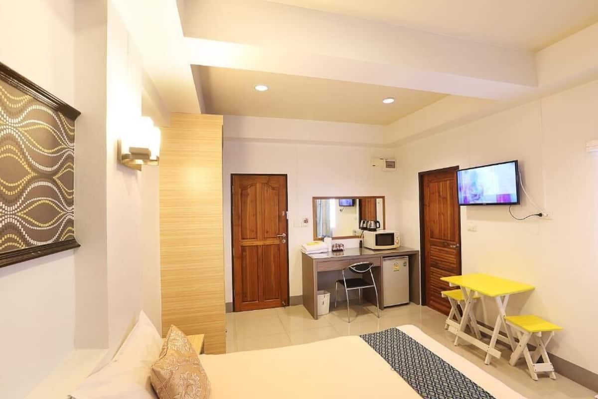 Une chambre d’hôtel équipée d’un lit, d’un bureau, d’une chaise, d’une télévision et d’une petite table avec des chaises.