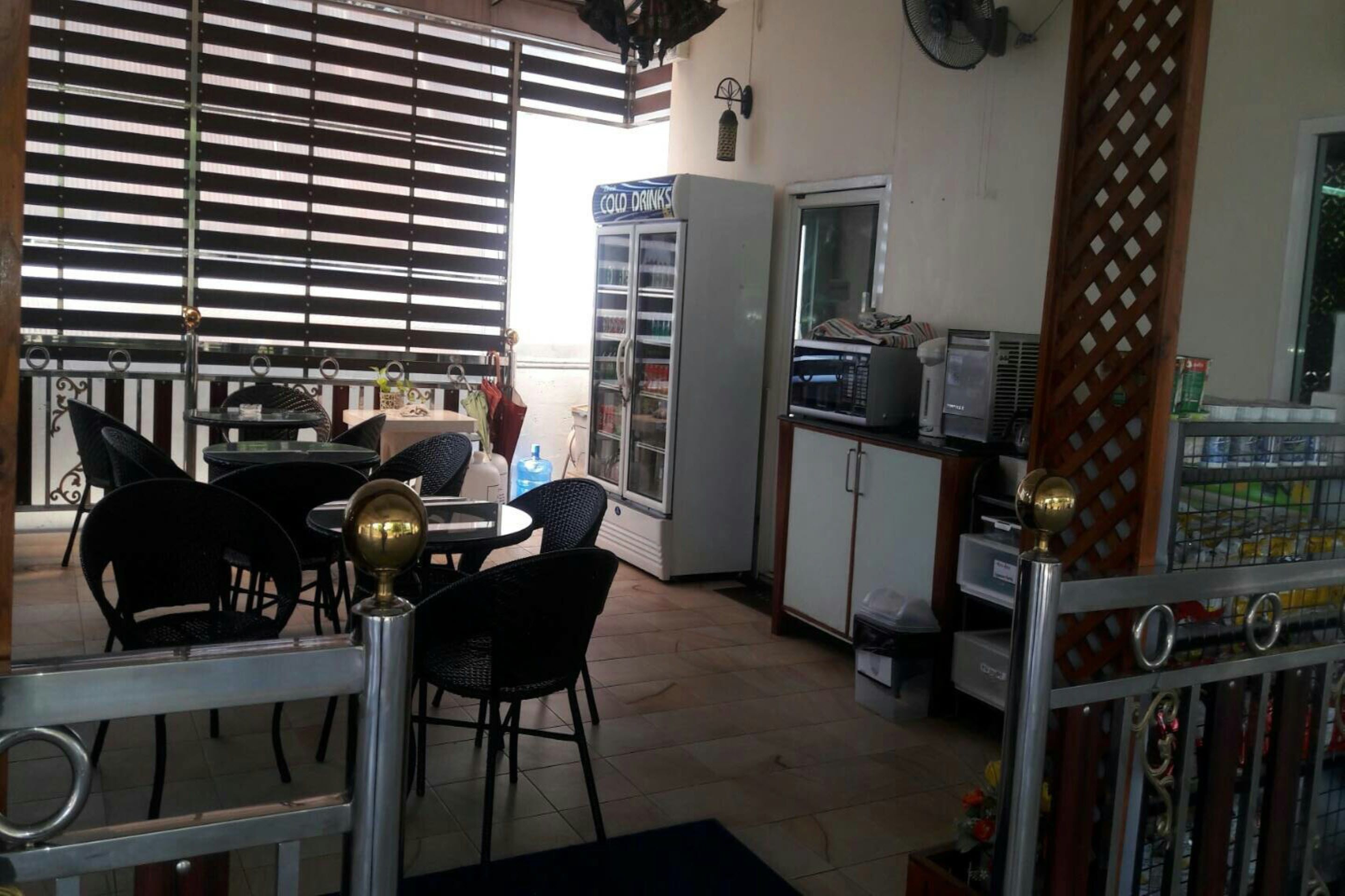 Una cafetería con zona de estar, un refrigerador que dice 'COLD DRINKS' y un microondas.