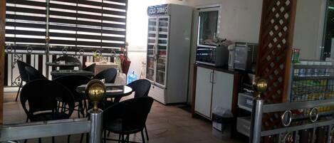 Una cafetería con zona de estar, un refrigerador que dice 'COLD DRINKS' y un microondas.