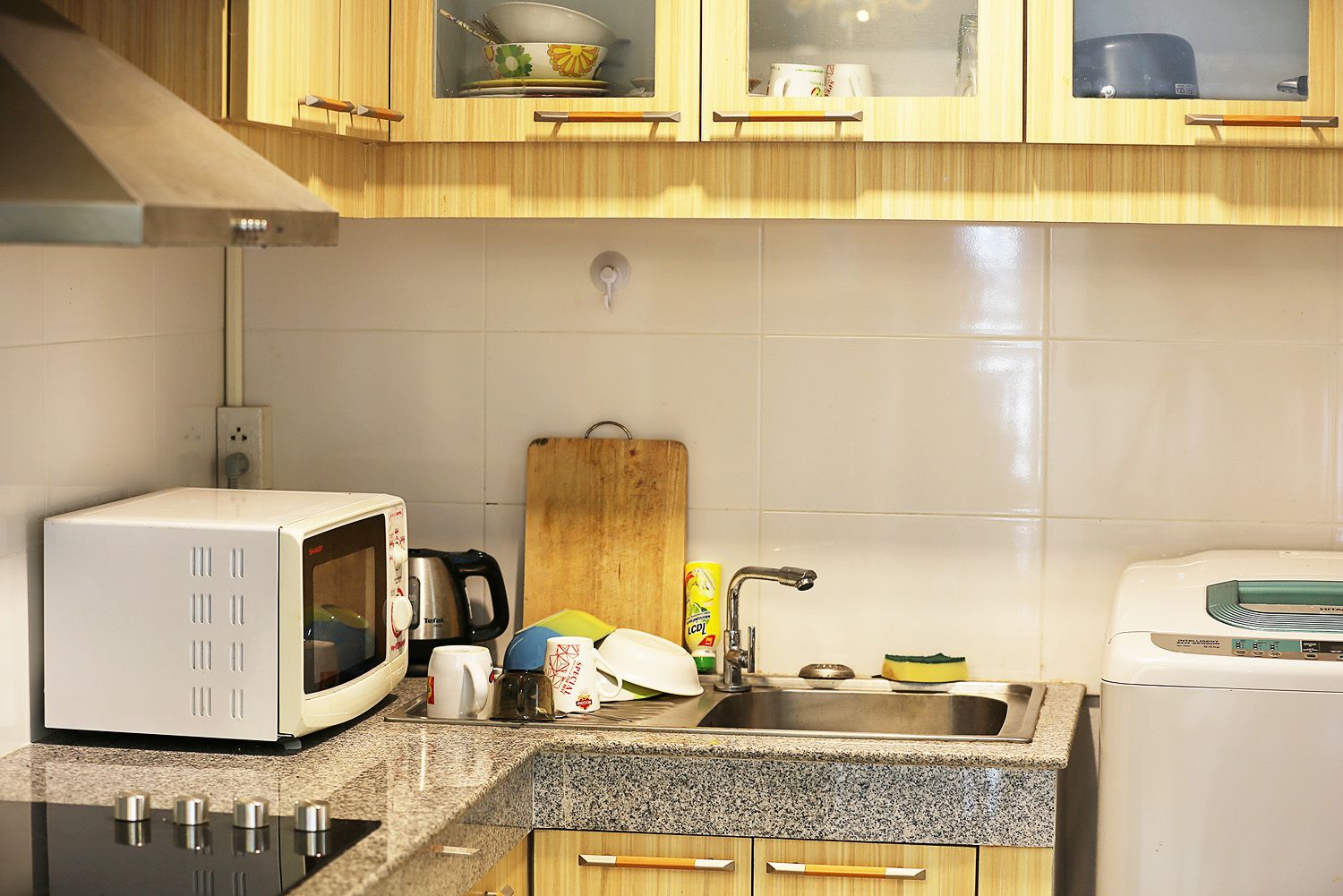 Una cocina con microondas, hervidor de agua, lavabo y tostadora.