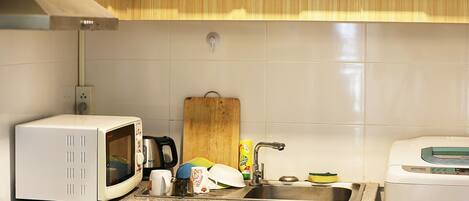 Una cocina con microondas, hervidor de agua, lavabo y tostadora.