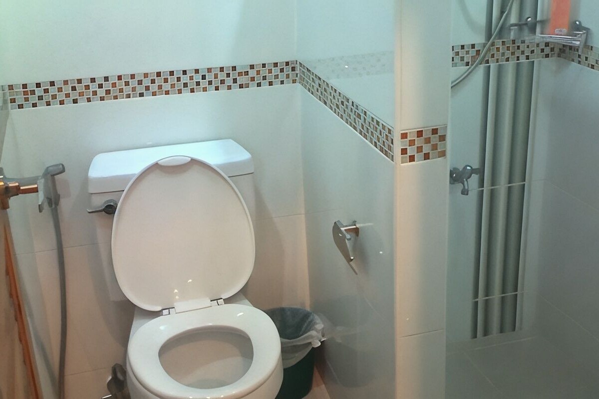 A bathroom with a toilet, a shower, and a tiled floor.