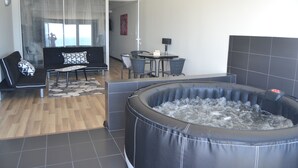 Un salon moderne avec un canapé noir, une table basse et un grand jacuzzi noir.