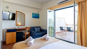 Une chambre d’hôtel équipée d’un lit, d’un bureau, d’une chaise, d’une télévision et d’un balcon avec des chaises.