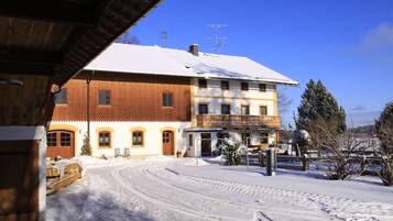 Ein zweistöckiges Gebäude mit verschneitem Dach und einem Balkon. Im Schnee sind deutliche Spuren zu sehen, die auf frische Aktivität hindeuten.