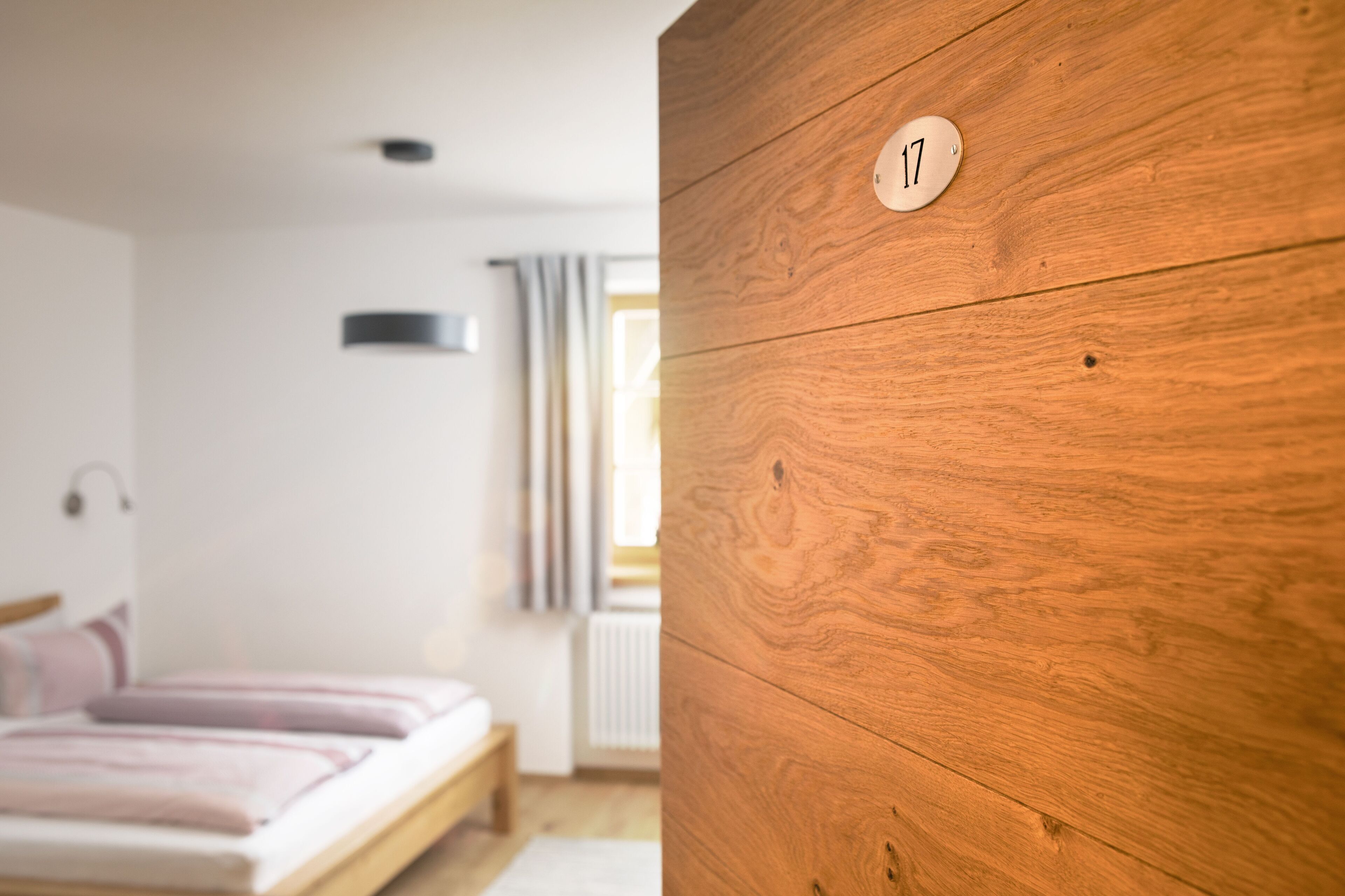 Ein Schlafzimmer mit einem Holzschrank, einem Bett mit rosa Bettwäsche und einem Fenster mit Vorhängen.
