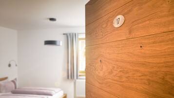 Ein Schlafzimmer mit einem Holzschrank, einem Bett mit rosa Bettwäsche und einem Fenster mit Vorhängen.