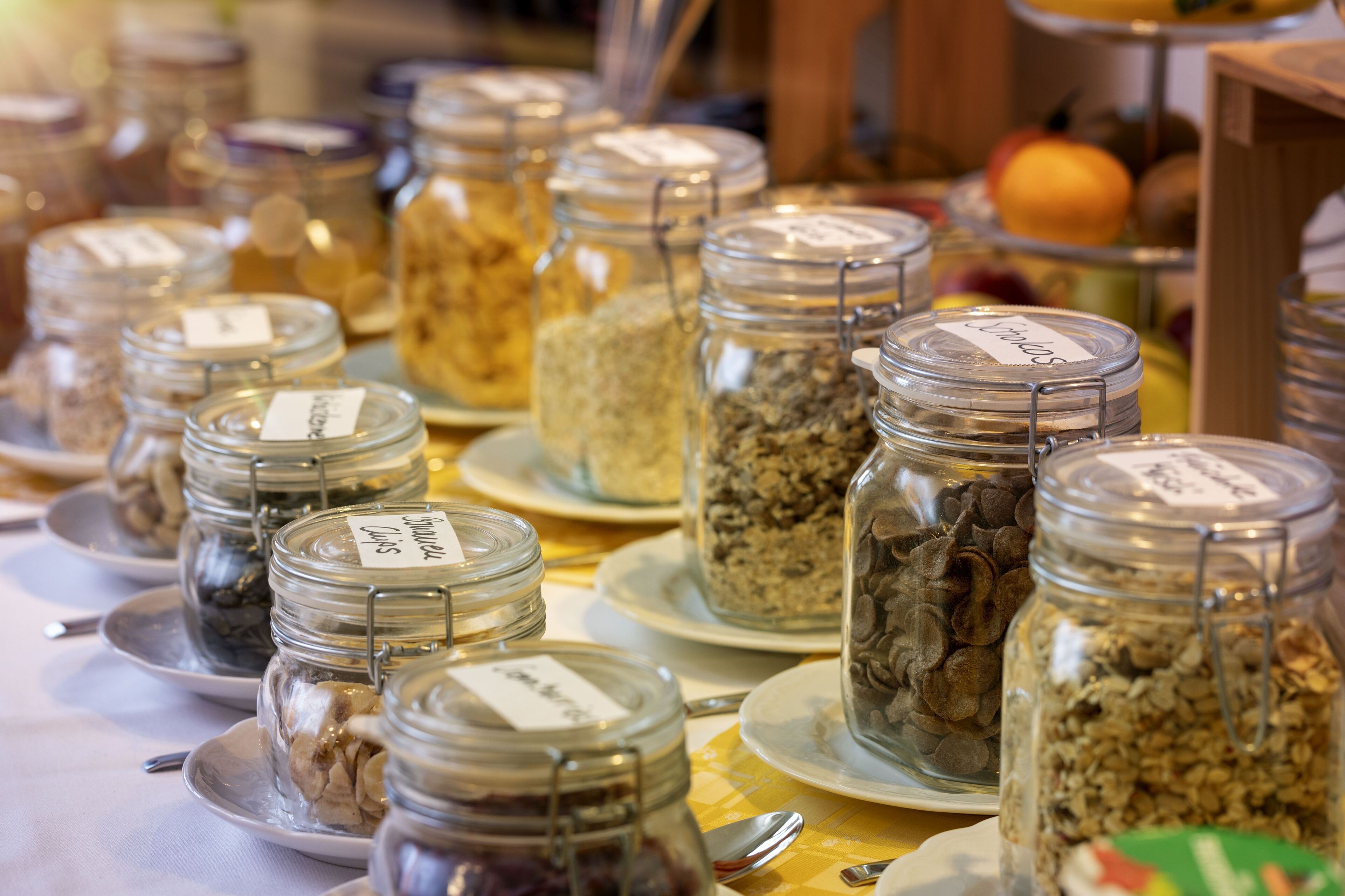 Una mesa con varios frascos de vidrio que contienen diferentes alimentos, cada uno con una etiqueta.