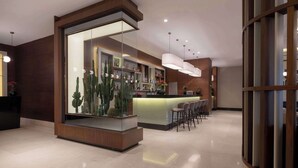 A modern bar area with a glass partition, shelves with bottles, and a seating area with bar stools. - Radisson Blu Hotel Ankara Cankaya (Ankara)