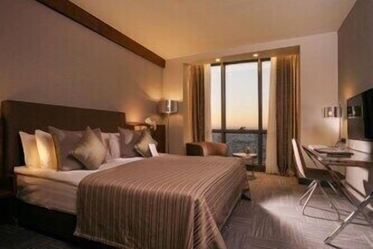A hotel room with a large bed, a desk, and a view of the city.