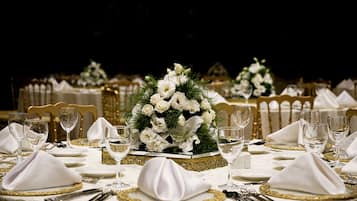 Una elegante mesa de comedor con manteles blancos, detalles dorados y centros de mesa florales.