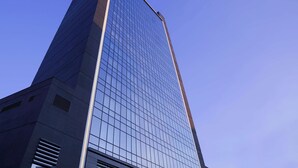 A tall, modern skyscraper with a glass facade and a prominent corner design. - Radisson Blu Hotel Ankara Cankaya (Ankara)