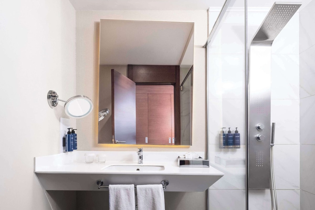 A modern bathroom with a large mirror, a sink, and a shower.