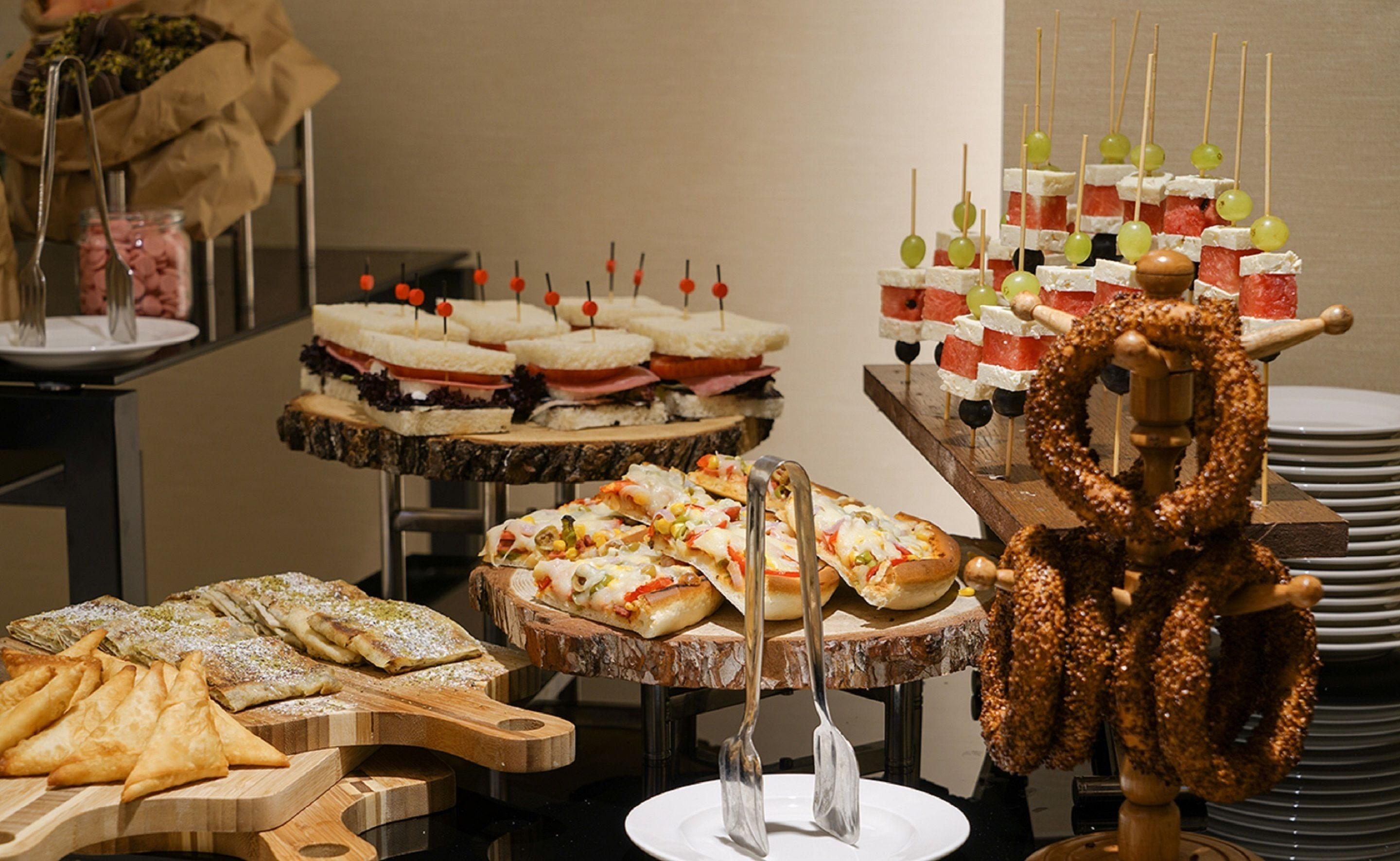 Ein reichhaltiges Buffet mit verschiedenen Speisen, darunter Sandwiches, Spieße und Gebäck.