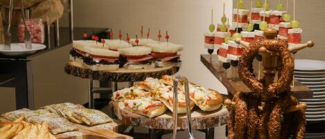 Ein reichhaltiges Buffet mit verschiedenen Speisen, darunter Sandwiches, Spieße und Gebäck.