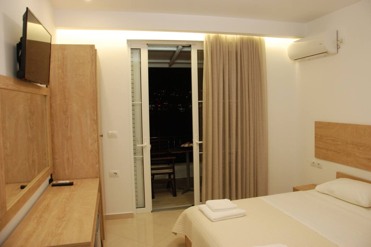Une chambre d’hôtel équipée d’un lit, d’une télévision, d’un bureau et d’une porte coulissante donnant sur un espace extérieur.