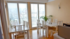 A dining area with a white table and chairs, a plant on the table, and a window with blinds. - Guesthouse Soul Ljubljana (Ljubljana)