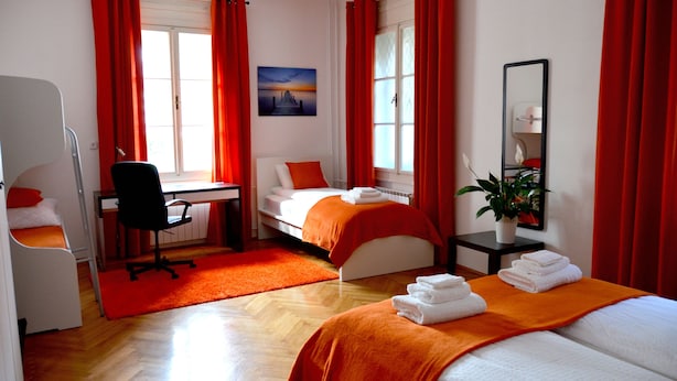 A hotel room with two beds, a desk, a chair, a small table with a plant, and a painting on the wall. - Guesthouse Soul Ljubljana (Ljubljana)