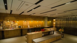 Una zona de recepción moderna con un mostrador de madera, un banco y una pared decorada con fotografías.
