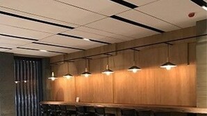 Un área de bar moderna con mostradores de madera, taburetes negros y un largo banco.