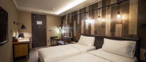 A hotel room with two beds, a desk with a laptop, a chair, and a small table.