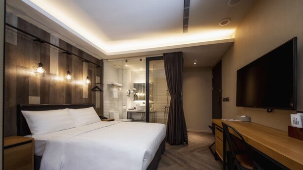 Una habitación de hotel moderna con una cama grande, un escritorio y un televisor.
