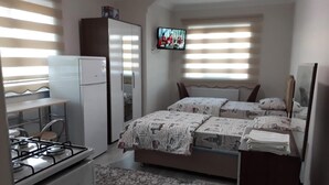A compact bedroom with a bed, a TV, and a kitchenette. - Moonlight (Erzincan)