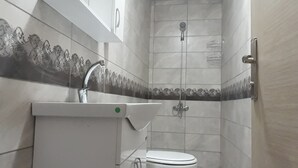 A small bathroom with a toilet, sink, and shower. - Moonlight (Erzincan)