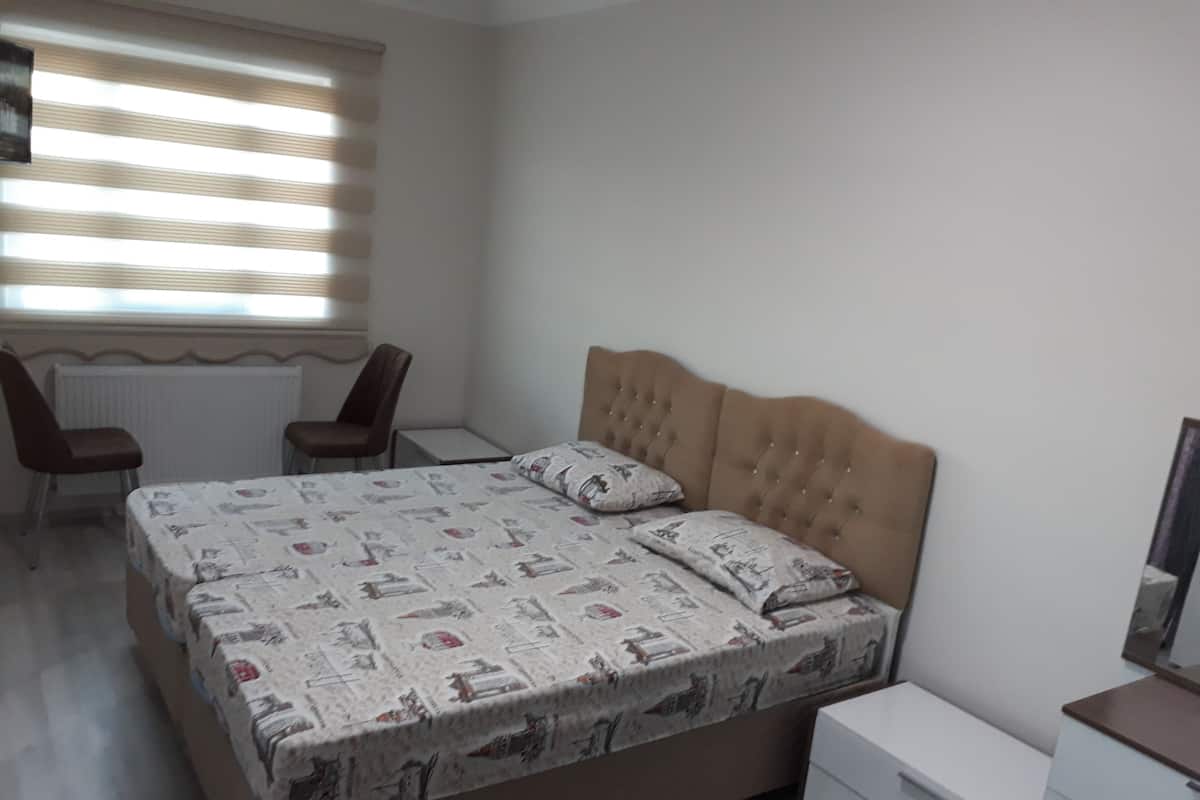 A bedroom with a bed, two chairs, a desk, and a dresser.