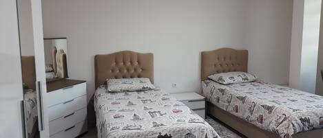 A bedroom with two beds, each with a patterned bedspread, a dresser, and a mirror.