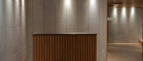 Un área de recepción con un mostrador de madera, paredes grises y suelo de madera.