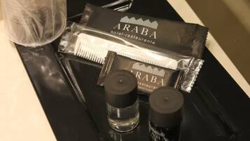 A tray with toiletries including a bottle of shampoo, a bottle of conditioner, and a packet of hairbrushes.