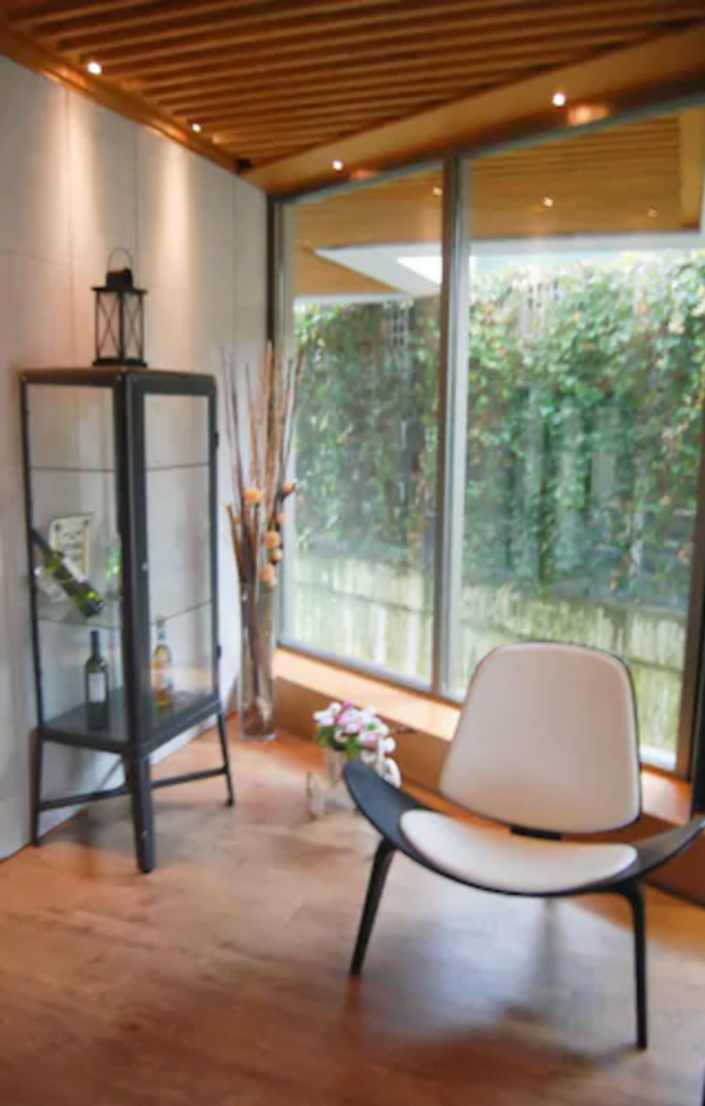 A modern interior with a large window, a black glass cabinet, and a white chair.