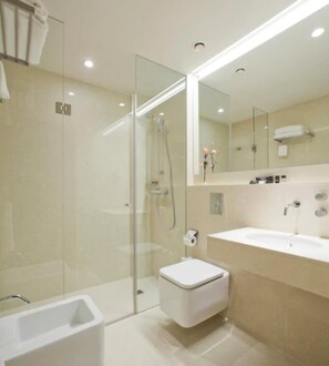 A modern bathroom with a glass-enclosed shower, a white toilet, and a sink with a mirror above it. - Hotel Restaurante Araba (Vitoria-Gasteiz)