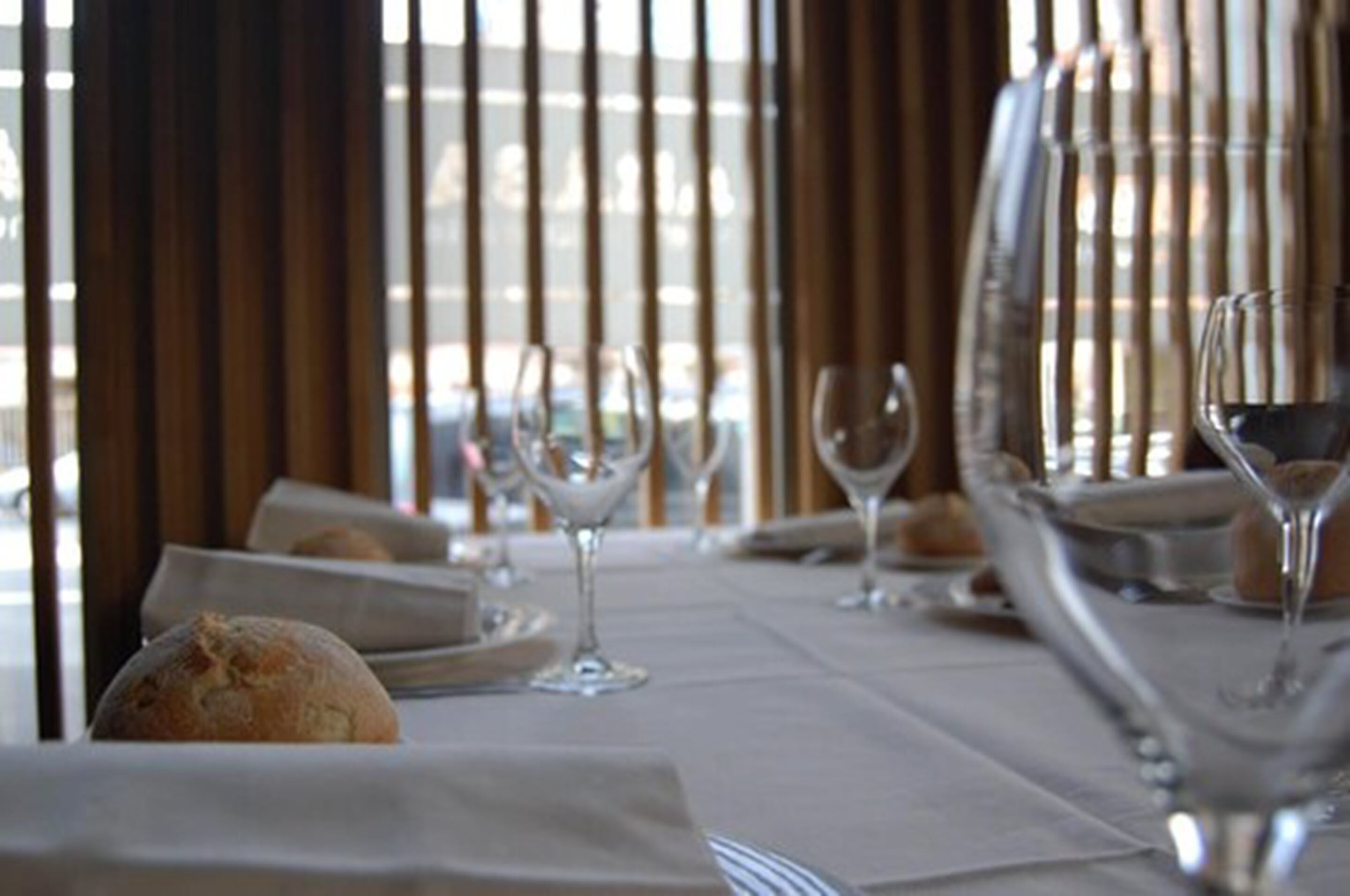 A dining table set with plates, glasses, and a loaf of bread.