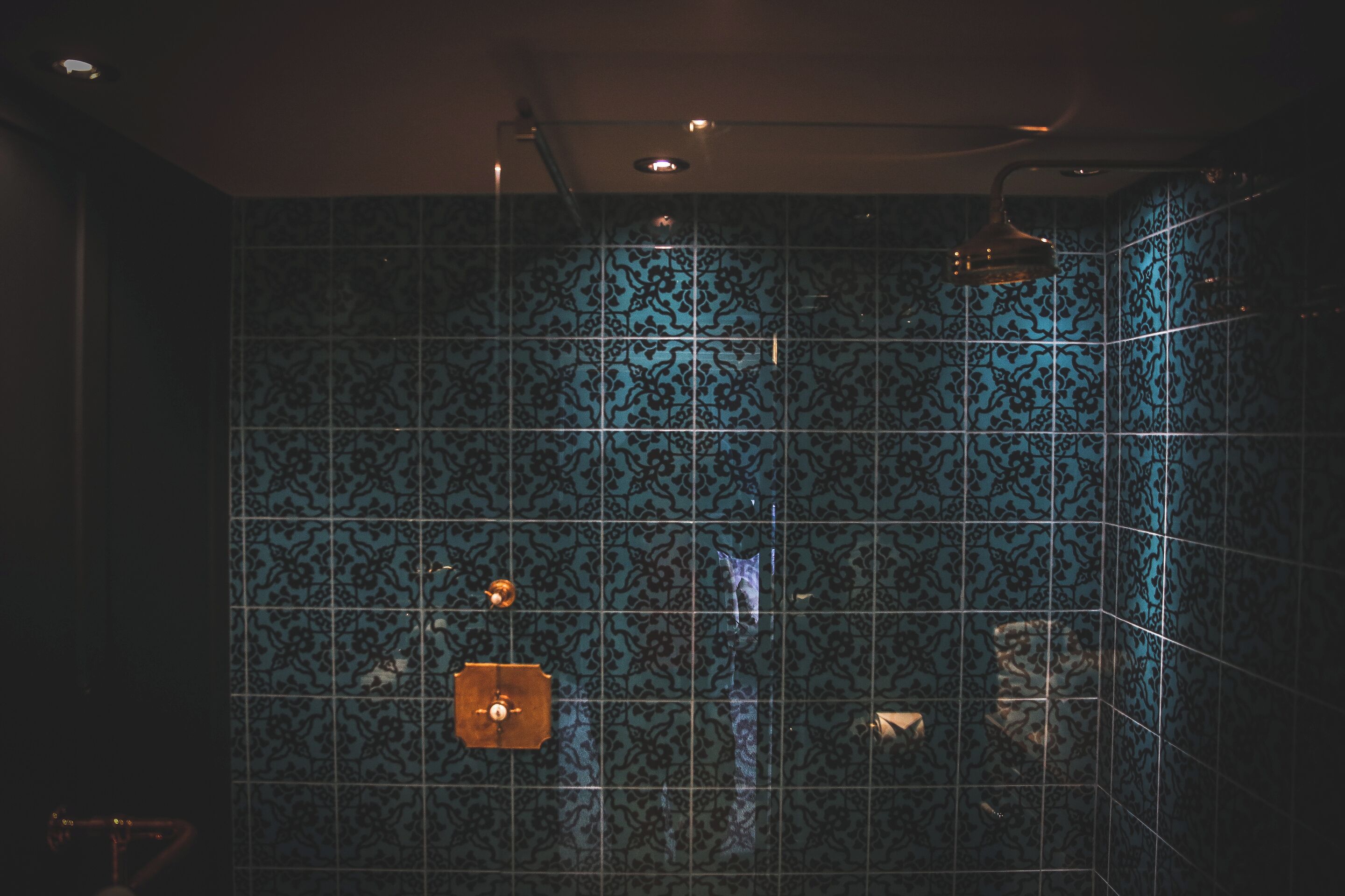 A bathroom with patterned tiles and a shower area.