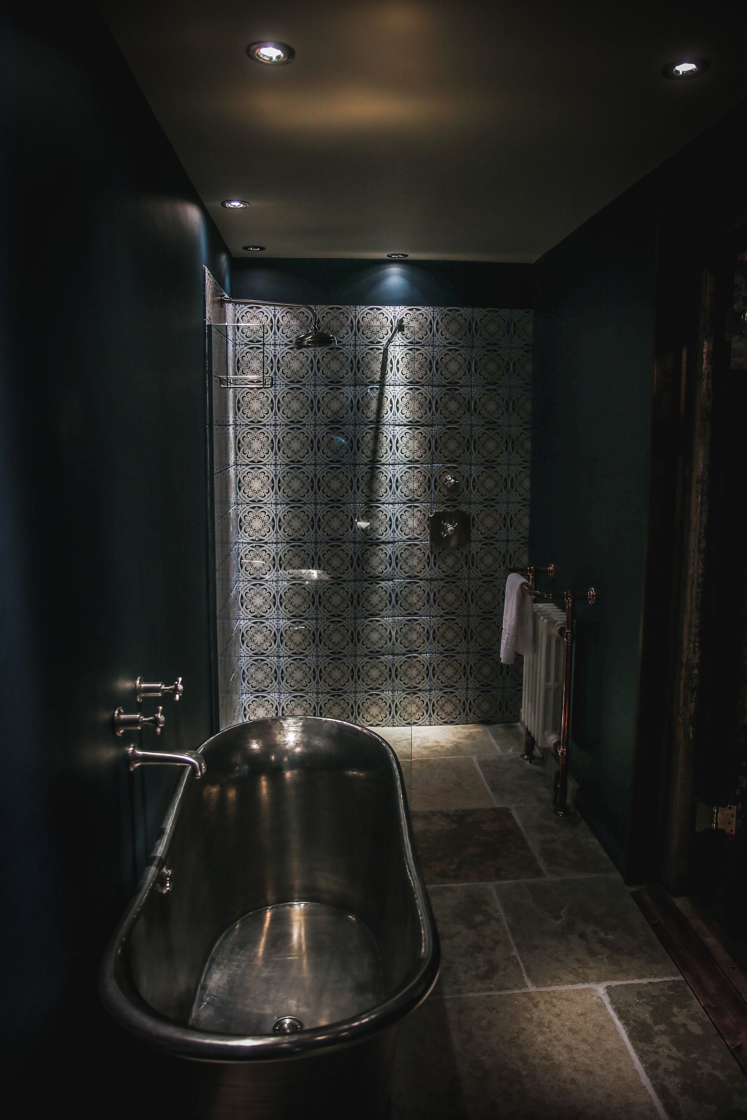 Un baño moderno con una bañera independiente, una ducha con un revestimiento decorativo y un perchero para toallas.