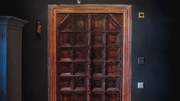 A room with a large wooden door, a chandelier, and a bed.