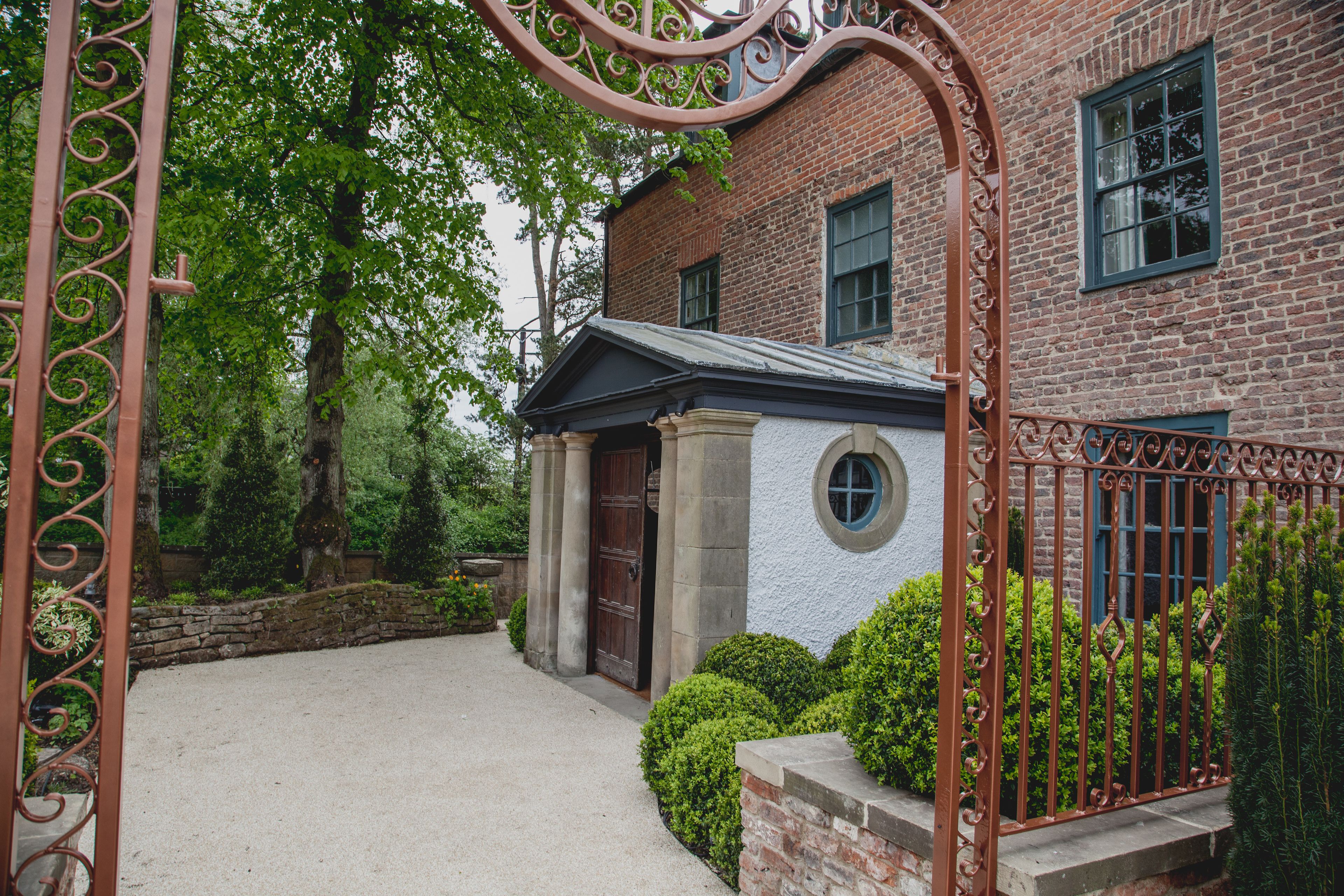 Ein Backsteinhaus mit Steineingang, rundem Fenster und einem Metallgitter.