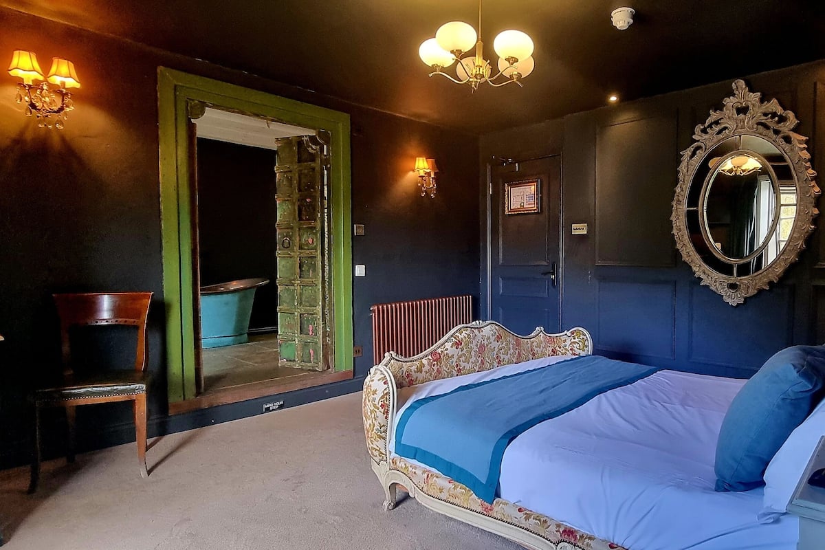 Une chambre à coucher avec un grand lit, un miroir, une commode et une chaise.