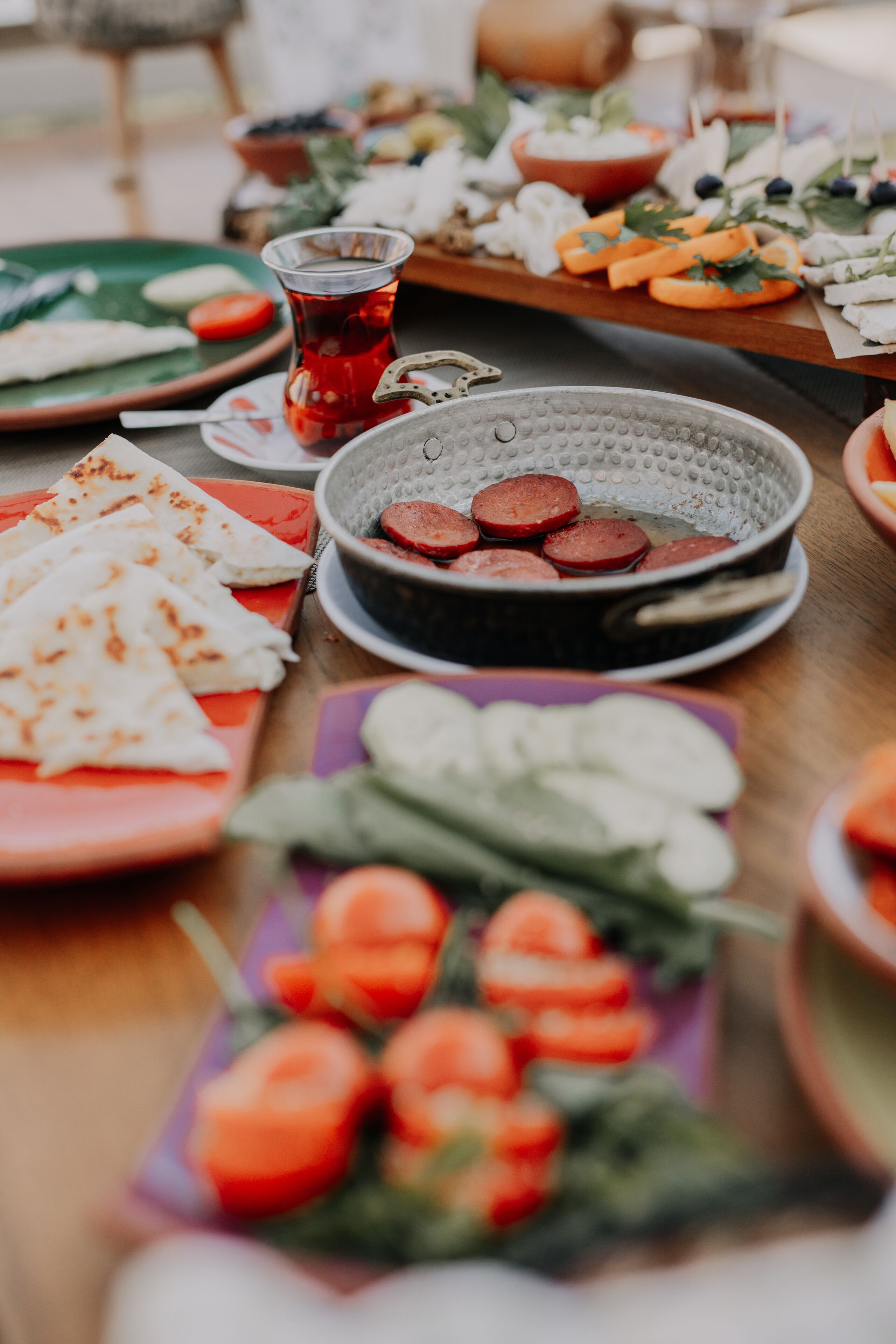Uma mesa com diversos alimentos, incluindo linguiça fatiada, queijo e legumes.