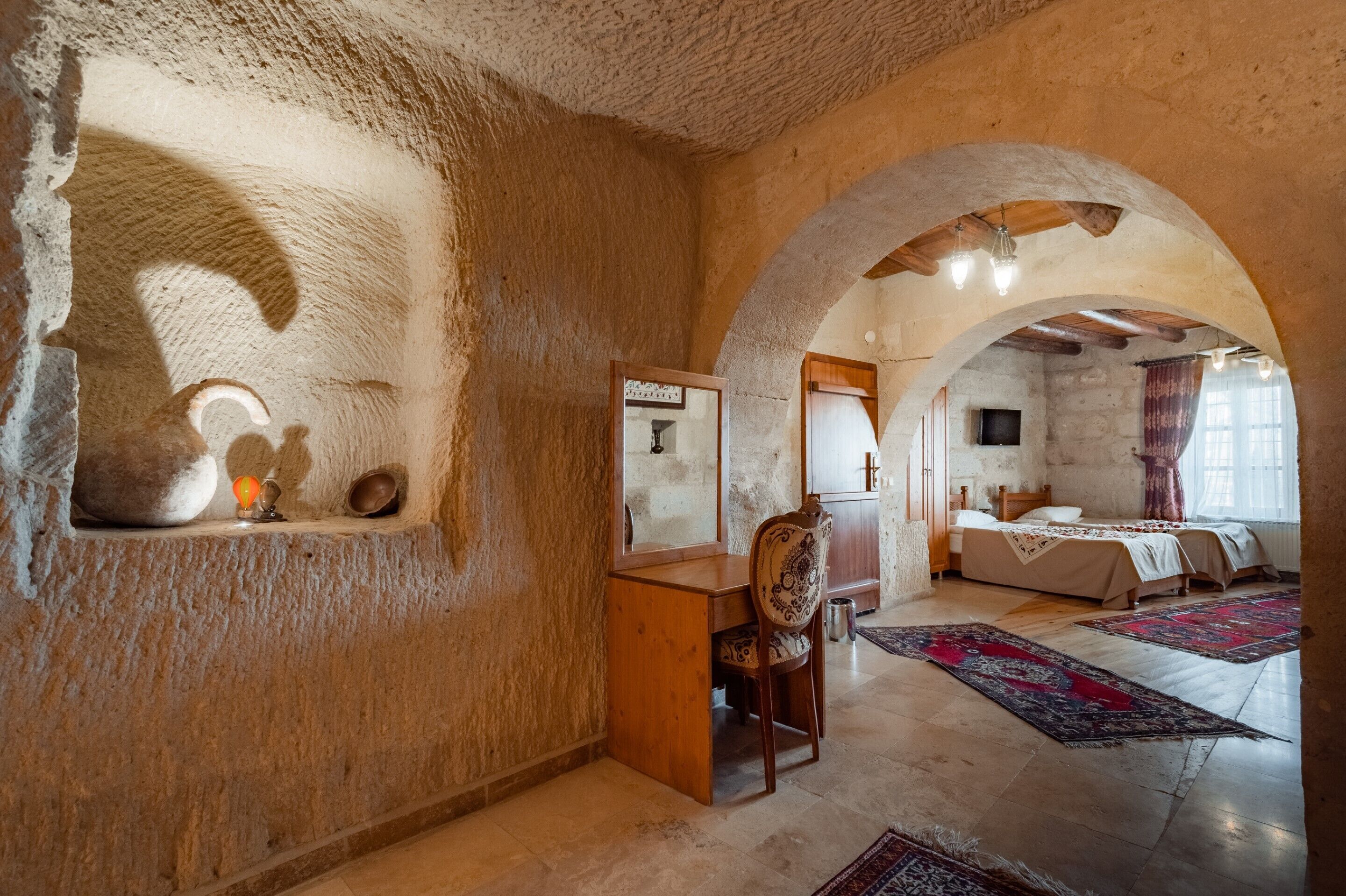 Una habitación rústica con pared de piedra, un escritorio de madera y una cama con dosel.
