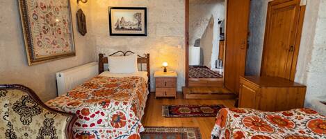 Une chambre confortable avec deux lits, une armoire en bois, une table de chevet avec une lampe et un tableau encadré au mur.