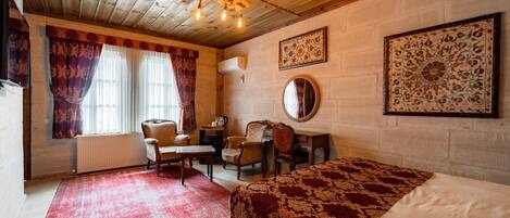 A cozy room with a wooden ceiling, a bed, a desk, a chair, and a radiator.