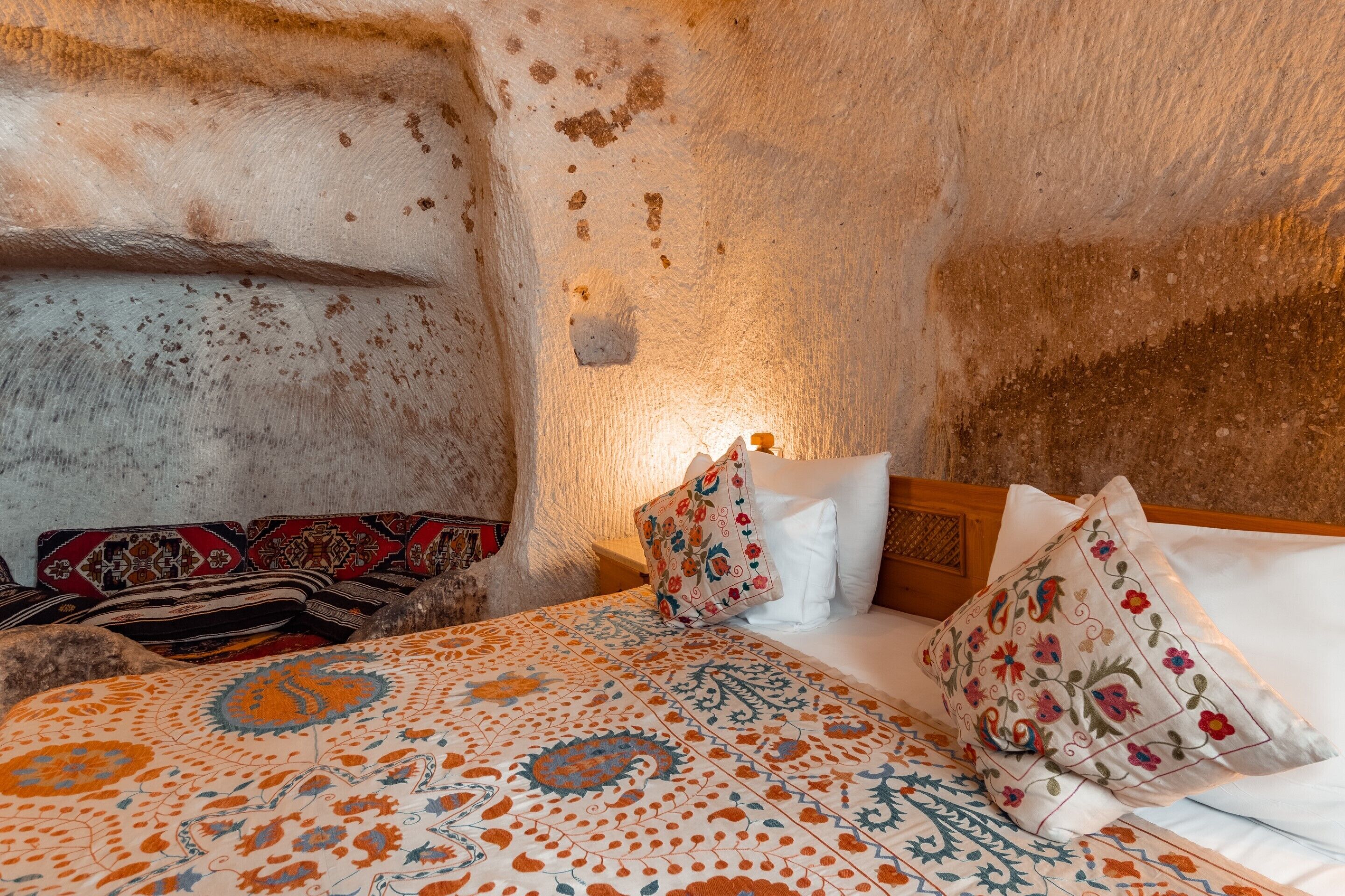 A cozy room with a bed, pillows, and a patterned bedspread.